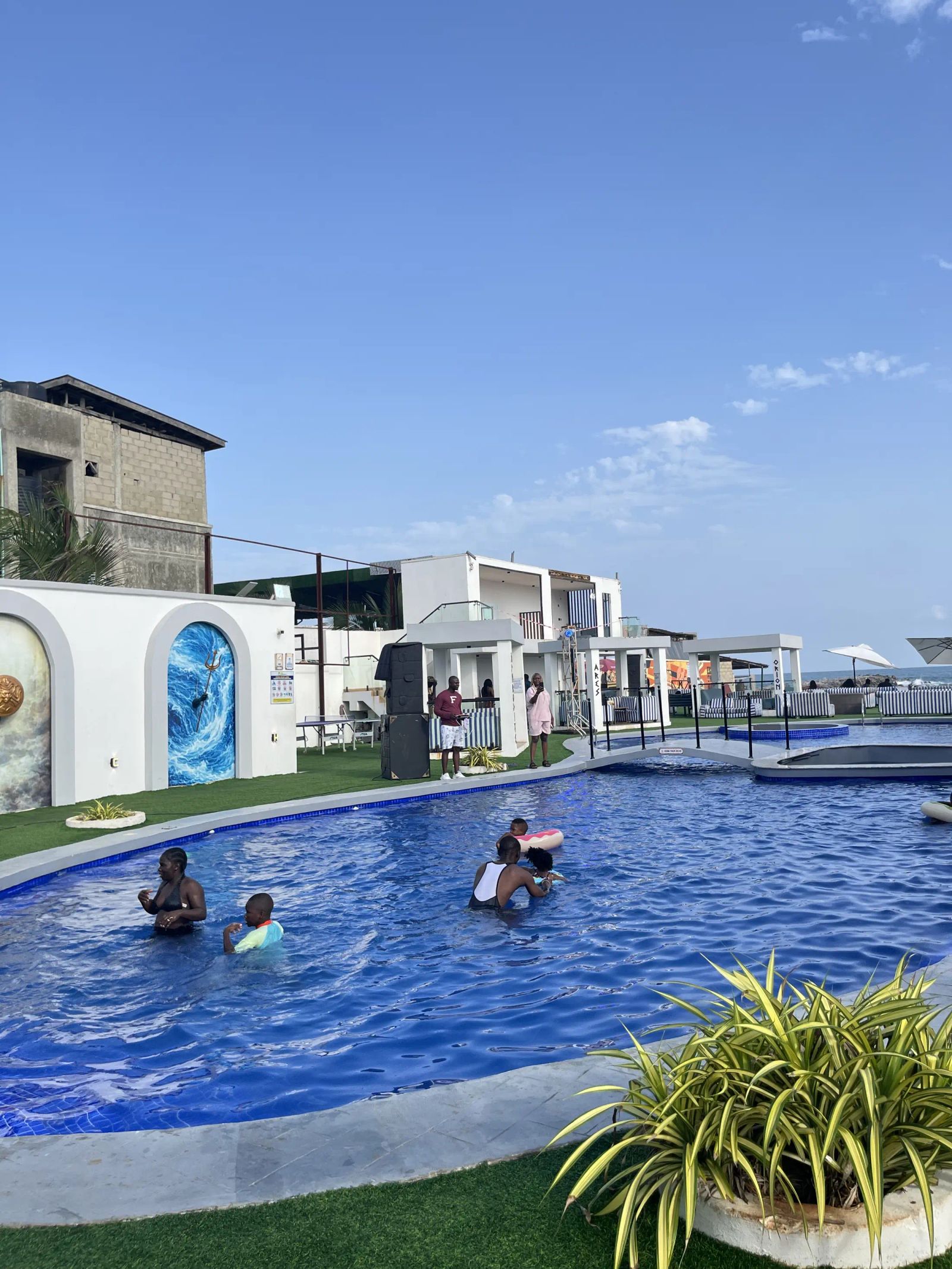Guests swimming in the lagoon pool, cabanas and painted arches behind
