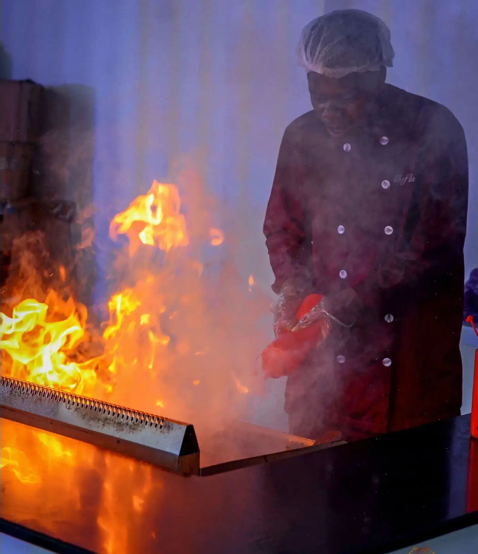 A chef at the grill, flames rising