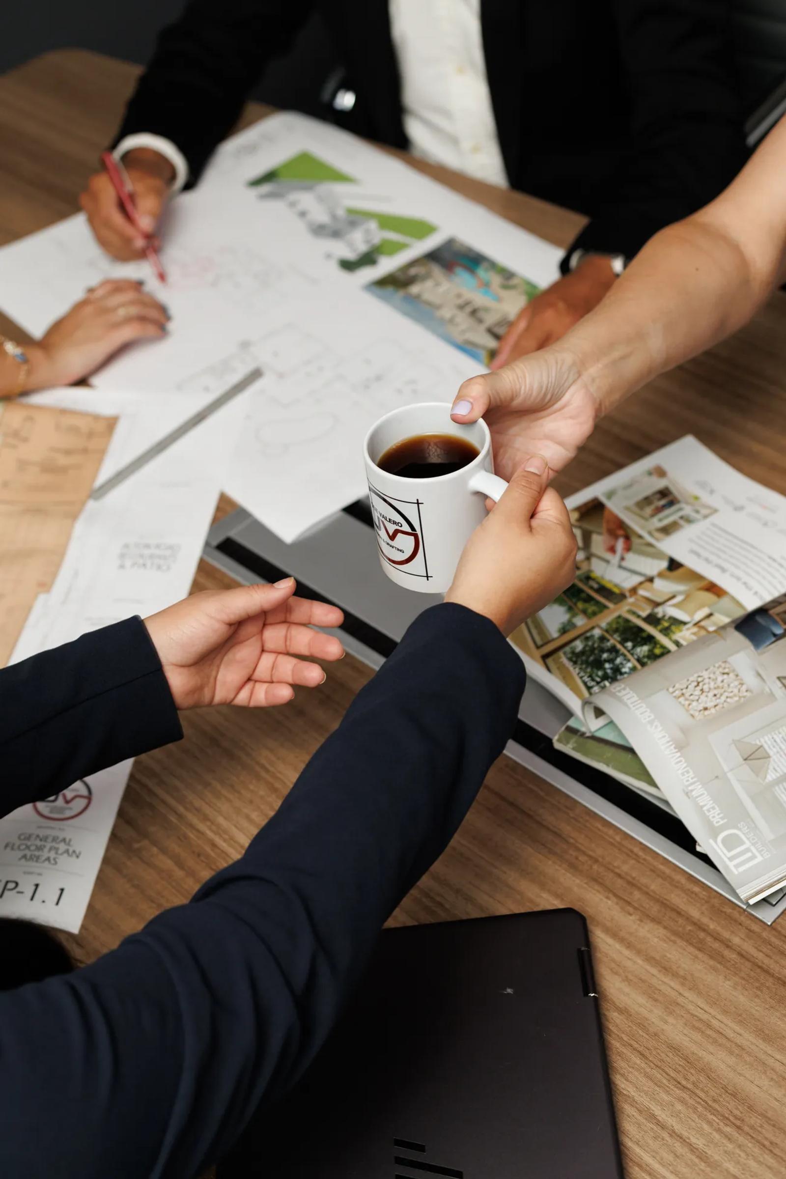 A handshake over architectural plans at the JV Design Services office