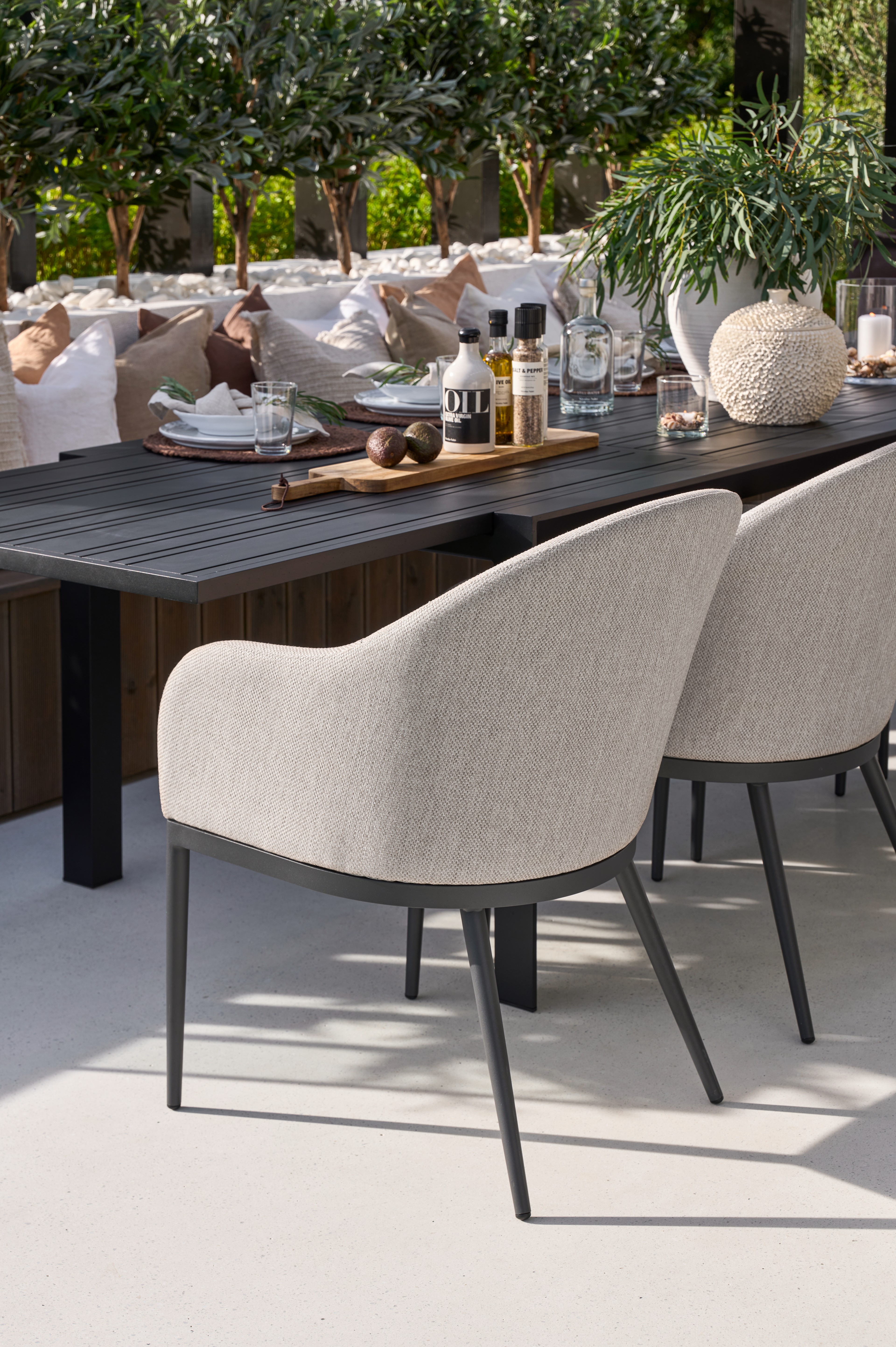 Umra stol i naturmateriale og Umra sidebord i tre, dekorert med puter, en vase og en plante