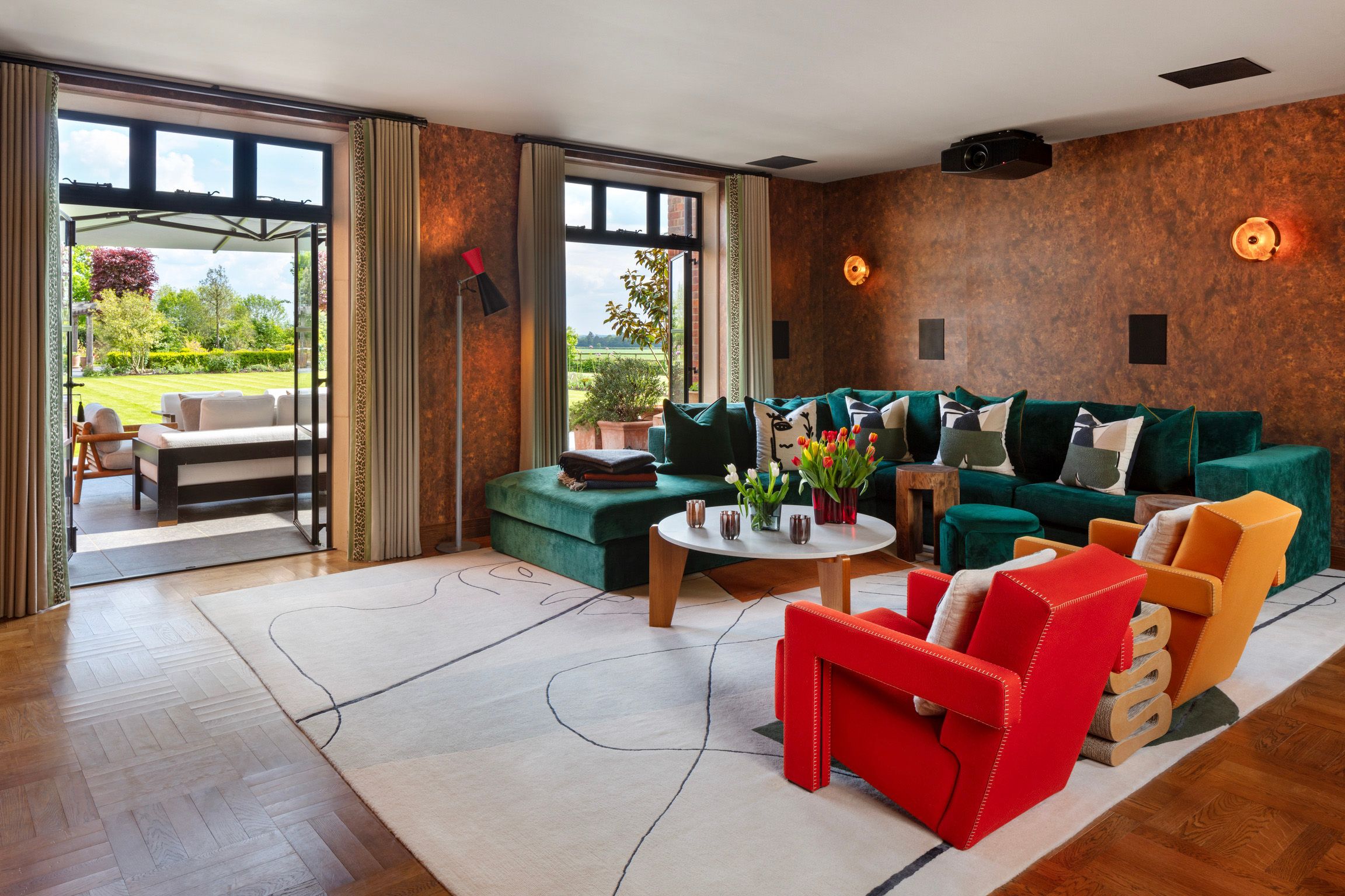 Living room with a ceiling-mounted projector, discreet wall speakers and full-height curtains