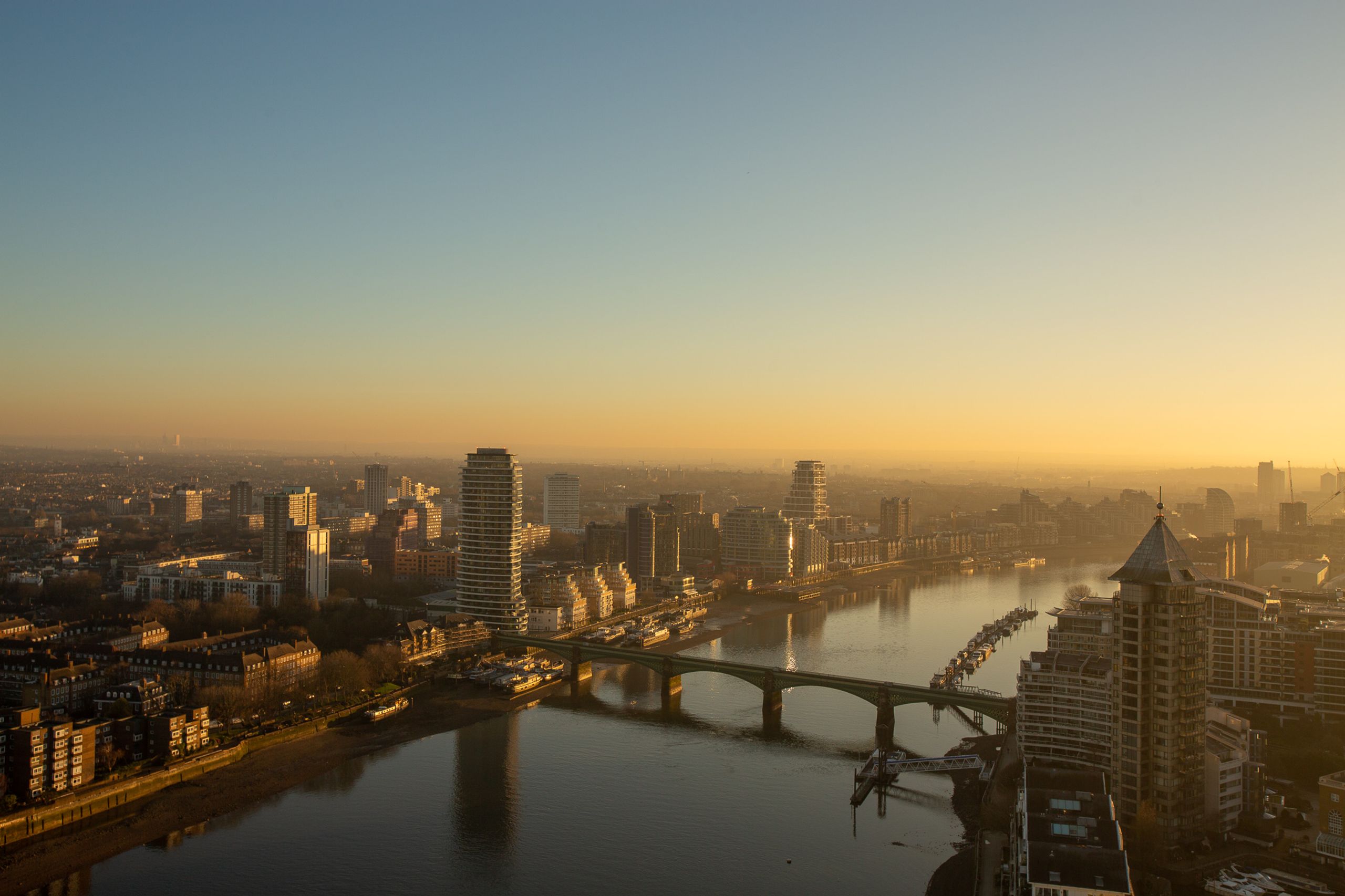Panoramic sunrise view of London skyline with river, bridges, and modern high-rise buildings