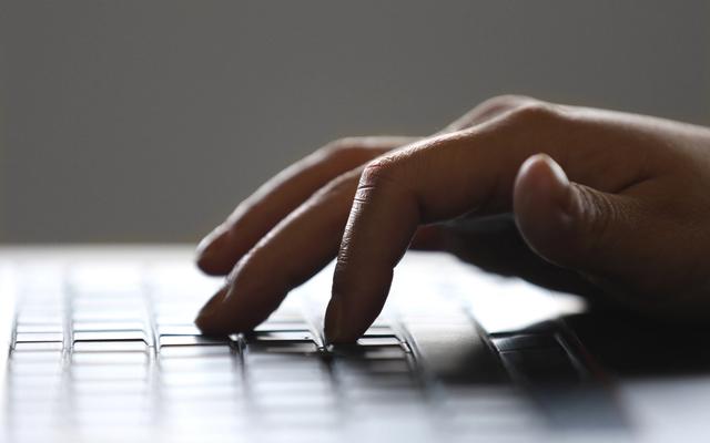 Hand typing on a laptop keyboard