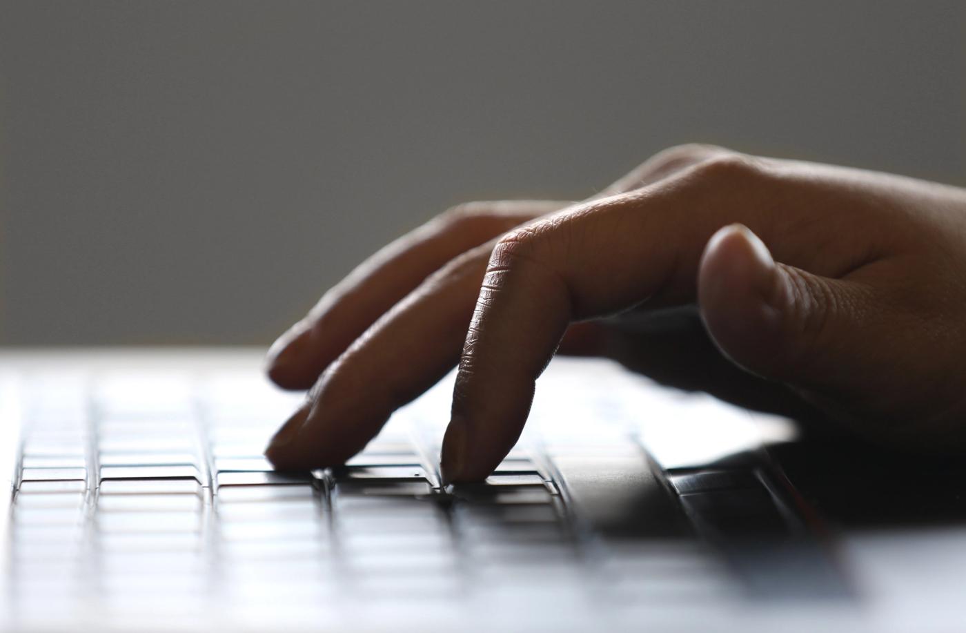 Hand typing on a laptop keyboard