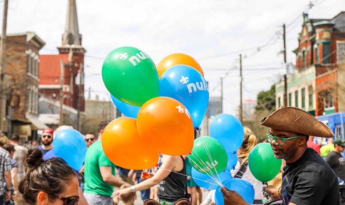 Man holds NuLu balloons on a crowded street in Louisville, KY.