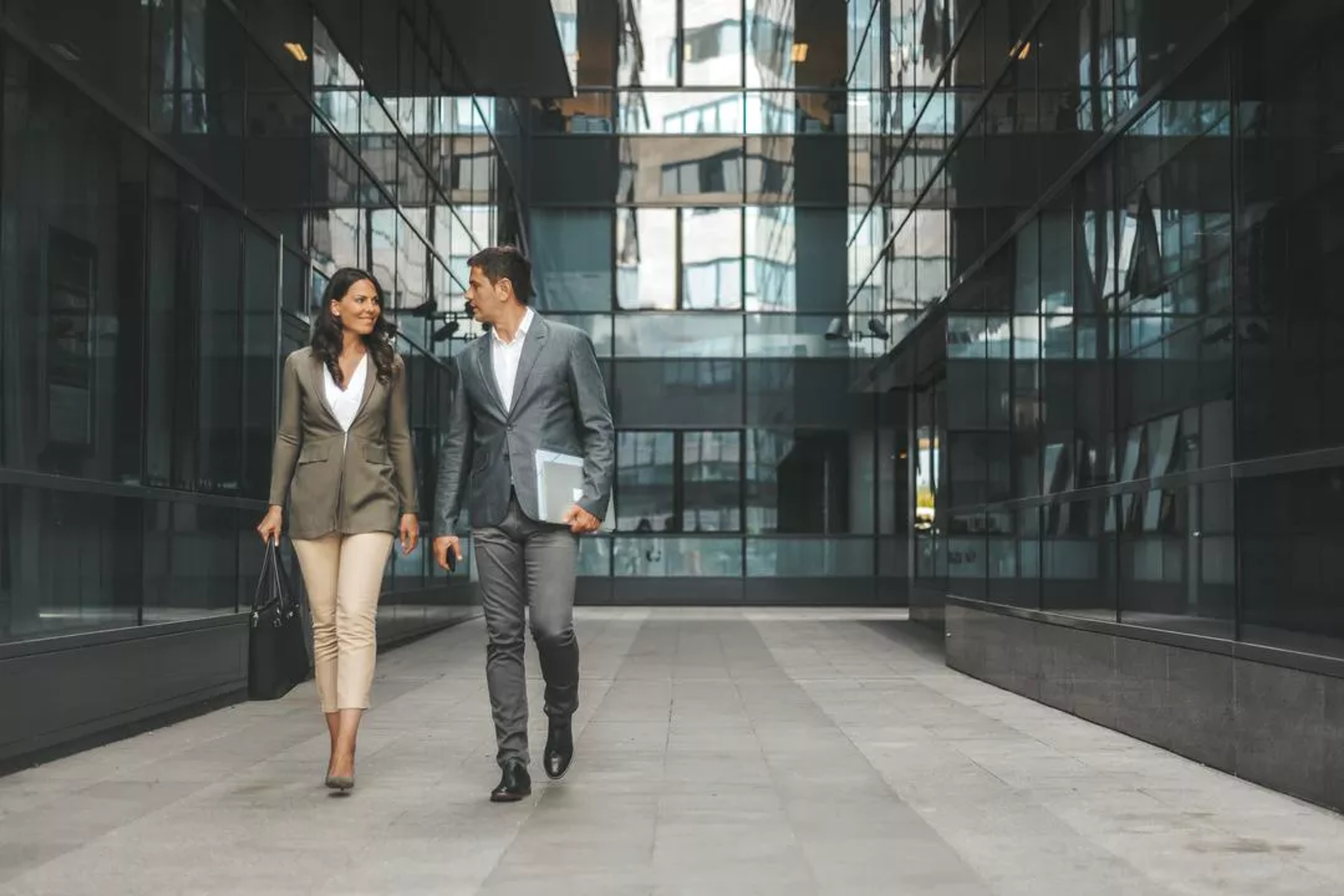 Man and woman in business attire walk through an office hallway together discussing cyber threats