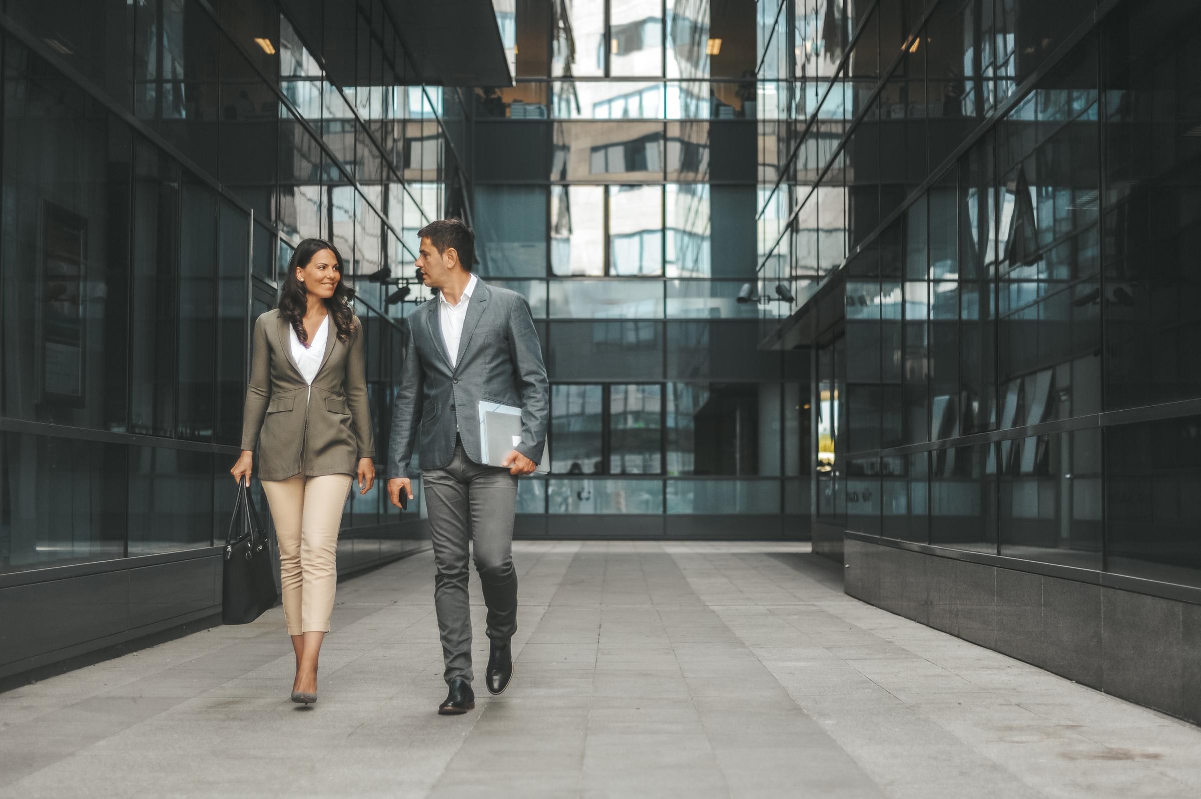 Board director committee members walk between corporate skyscrapers