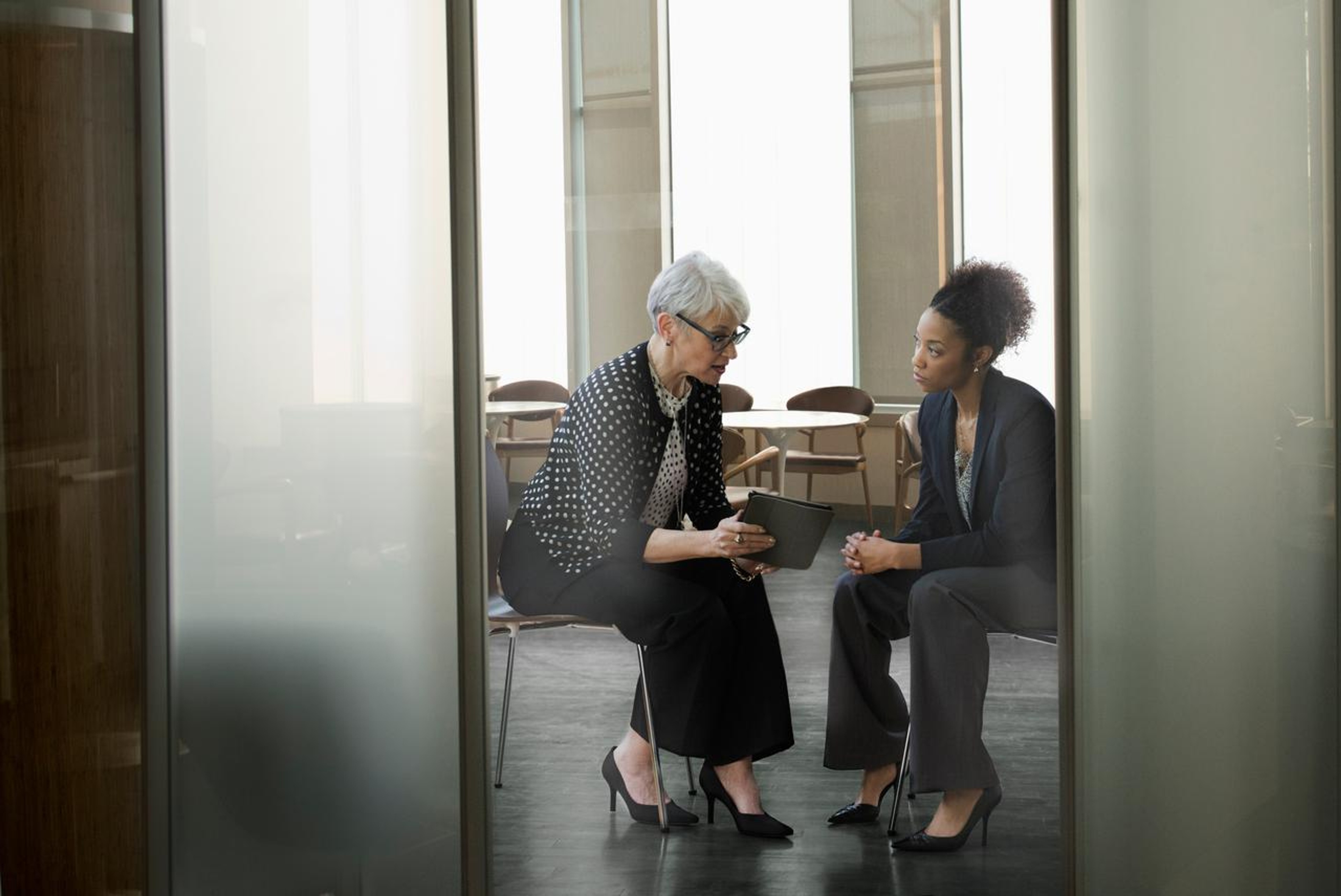 Women collaborating in a boardroom by sharing a tablet