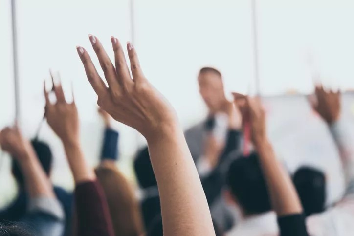 Members raise their hands during school board meeting