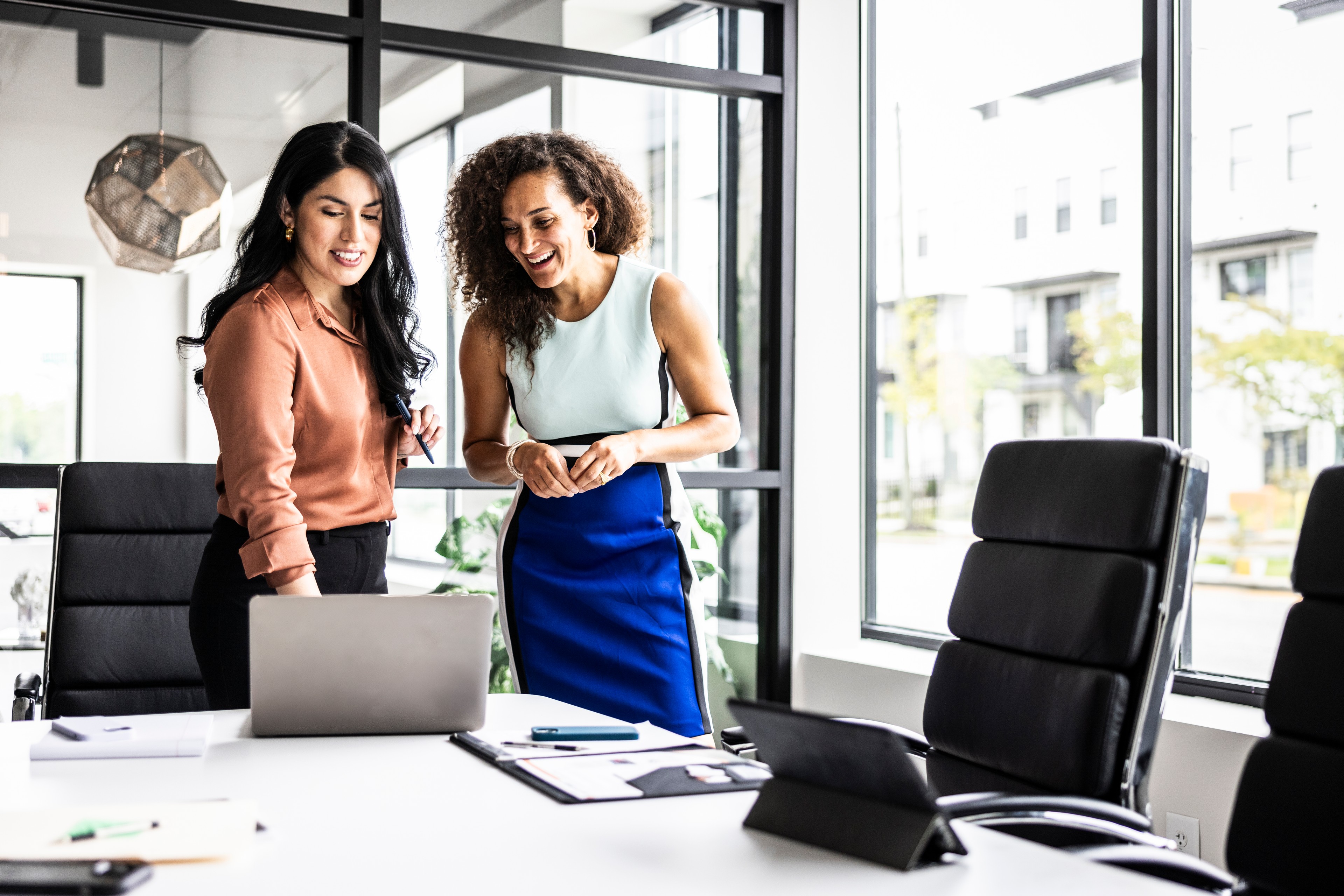 Businesswomen looking at laptop in modern conference room