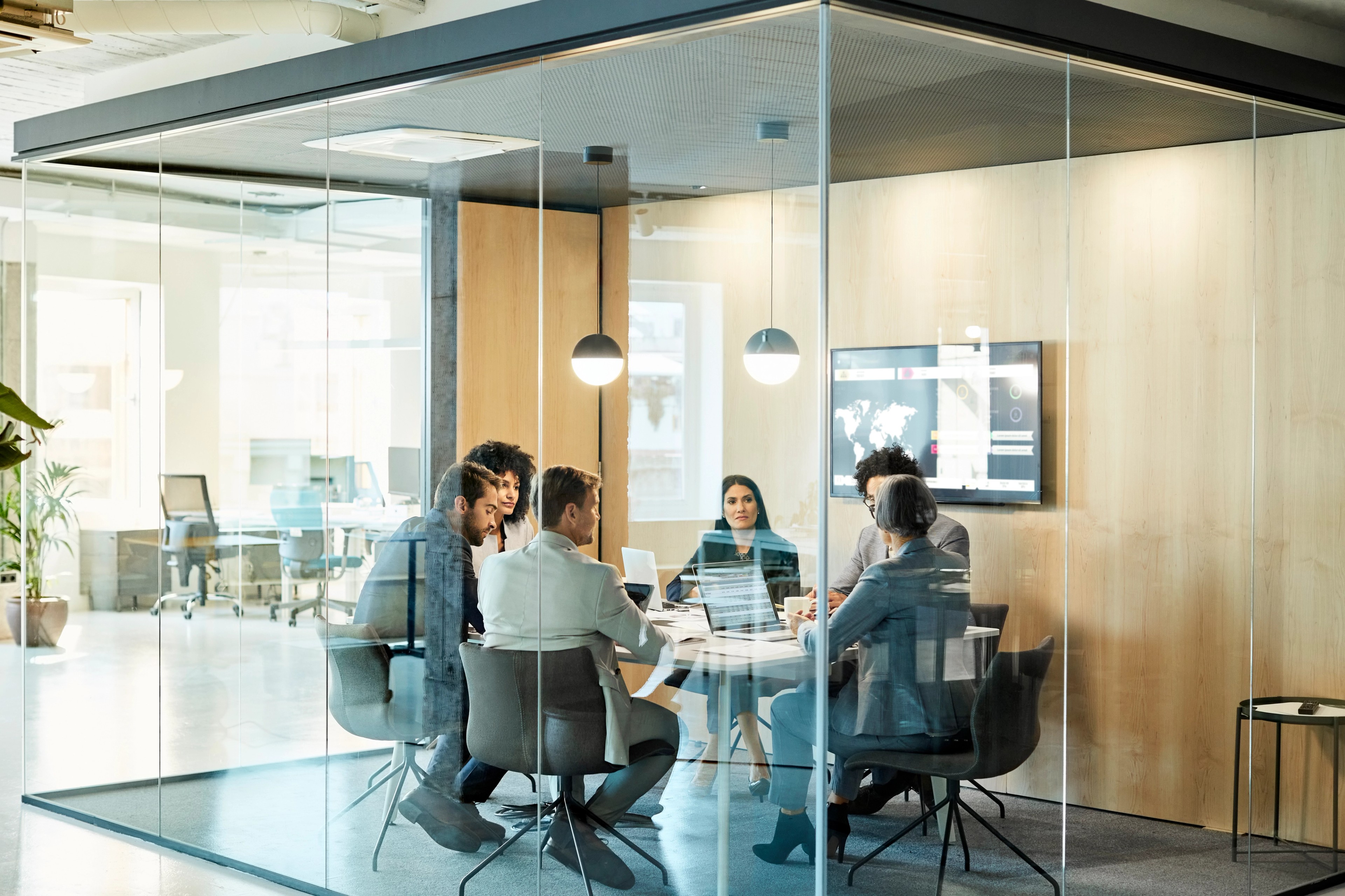 Business colleagues sitting at conference table seen through glass wall.