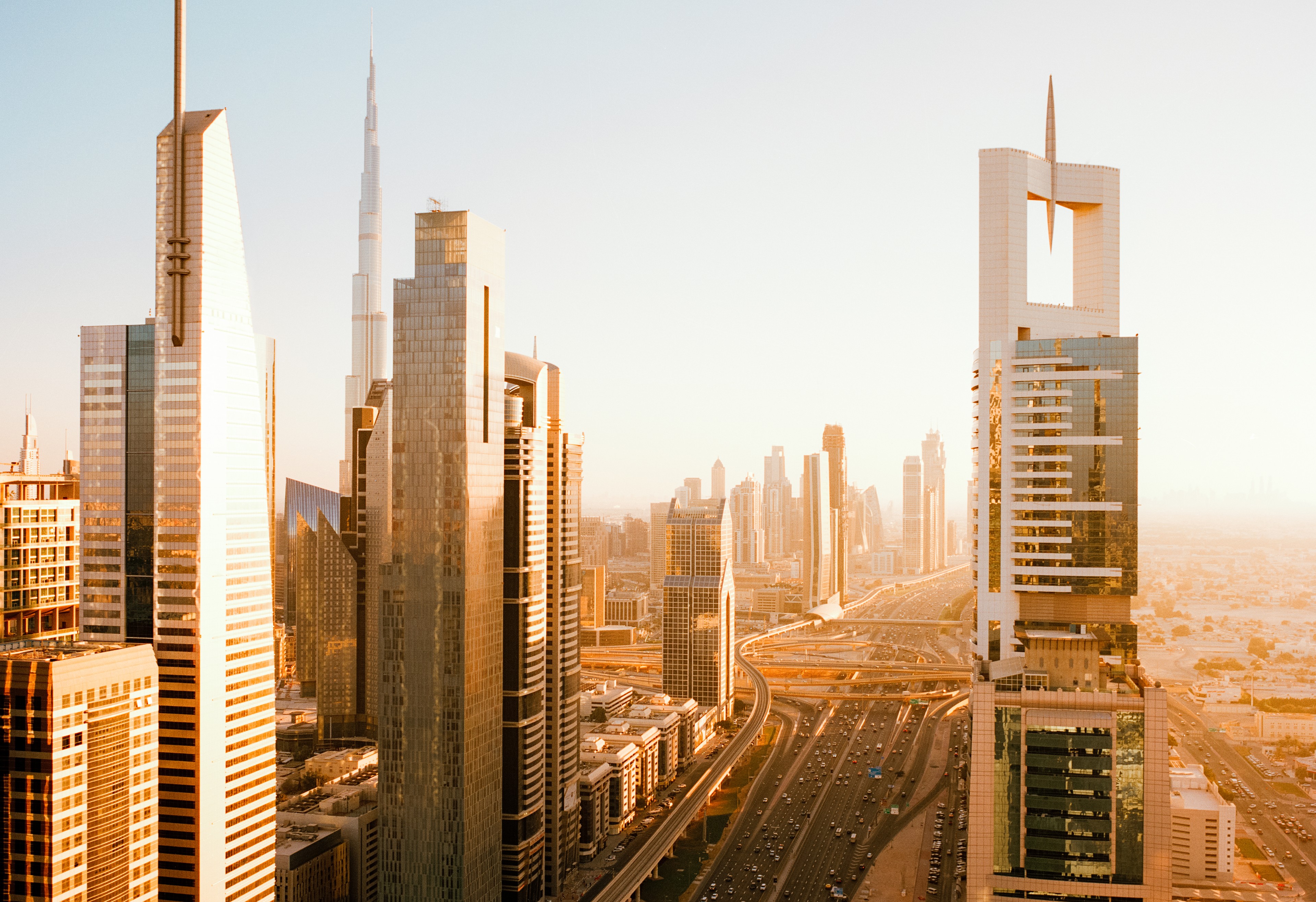 UAE, Dubai, Elevated view over busy Sheikh Zayed road with cars and skyscrapers in early morning sunlight
