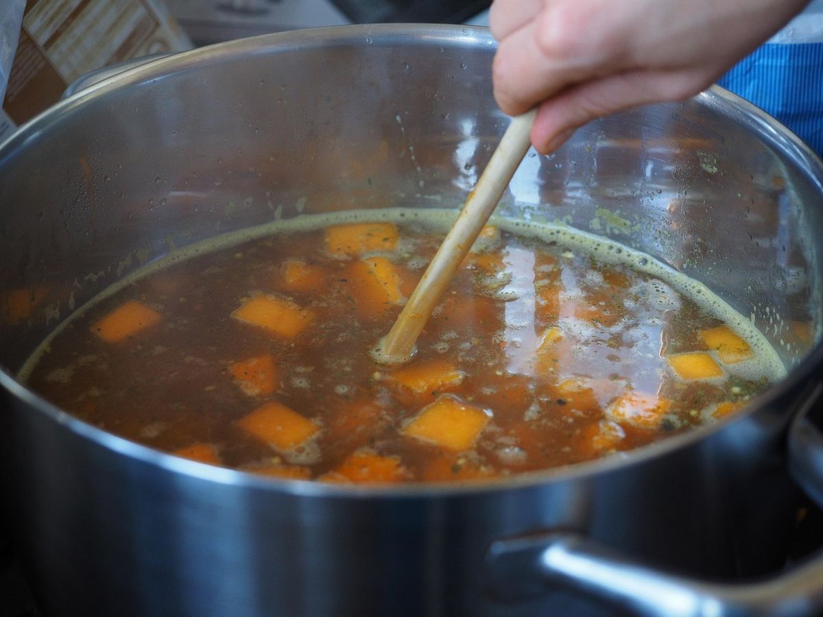 Een kookpan met groenten en bouillon op het vuur