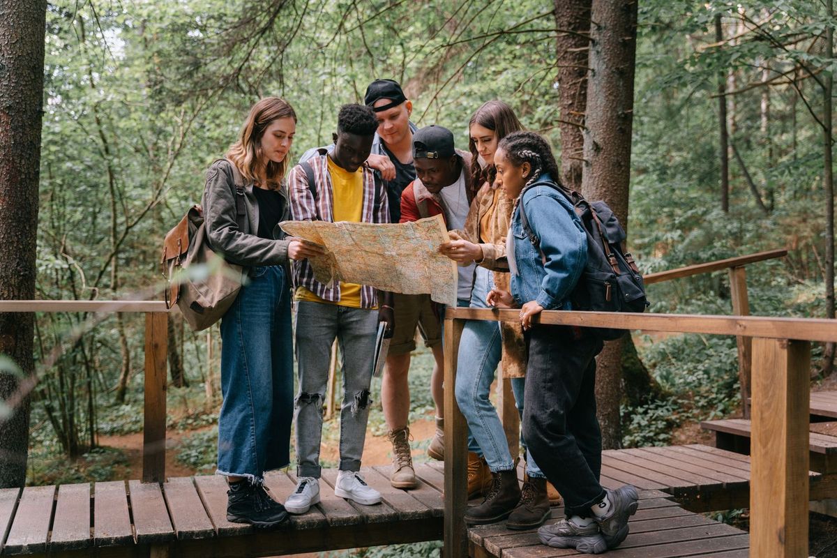 Een groep bekijkt samen een wandelkaart op een brug in het bos