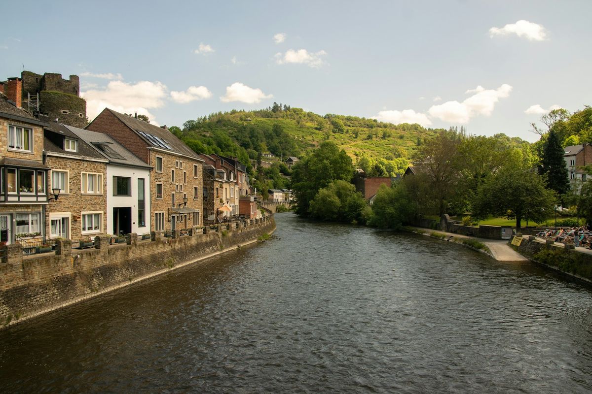 De Ourthe langs de stenen huizen van La Roche-en-Ardenne, met de kasteelruïne erboven