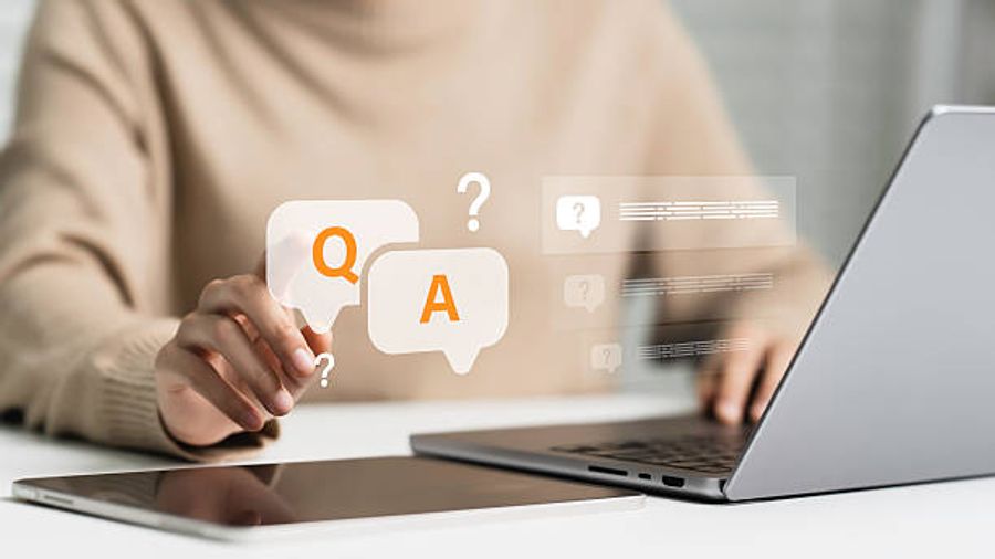 Person at a laptop pointing to Q and A speech bubble icons representing frequently asked questions and answers