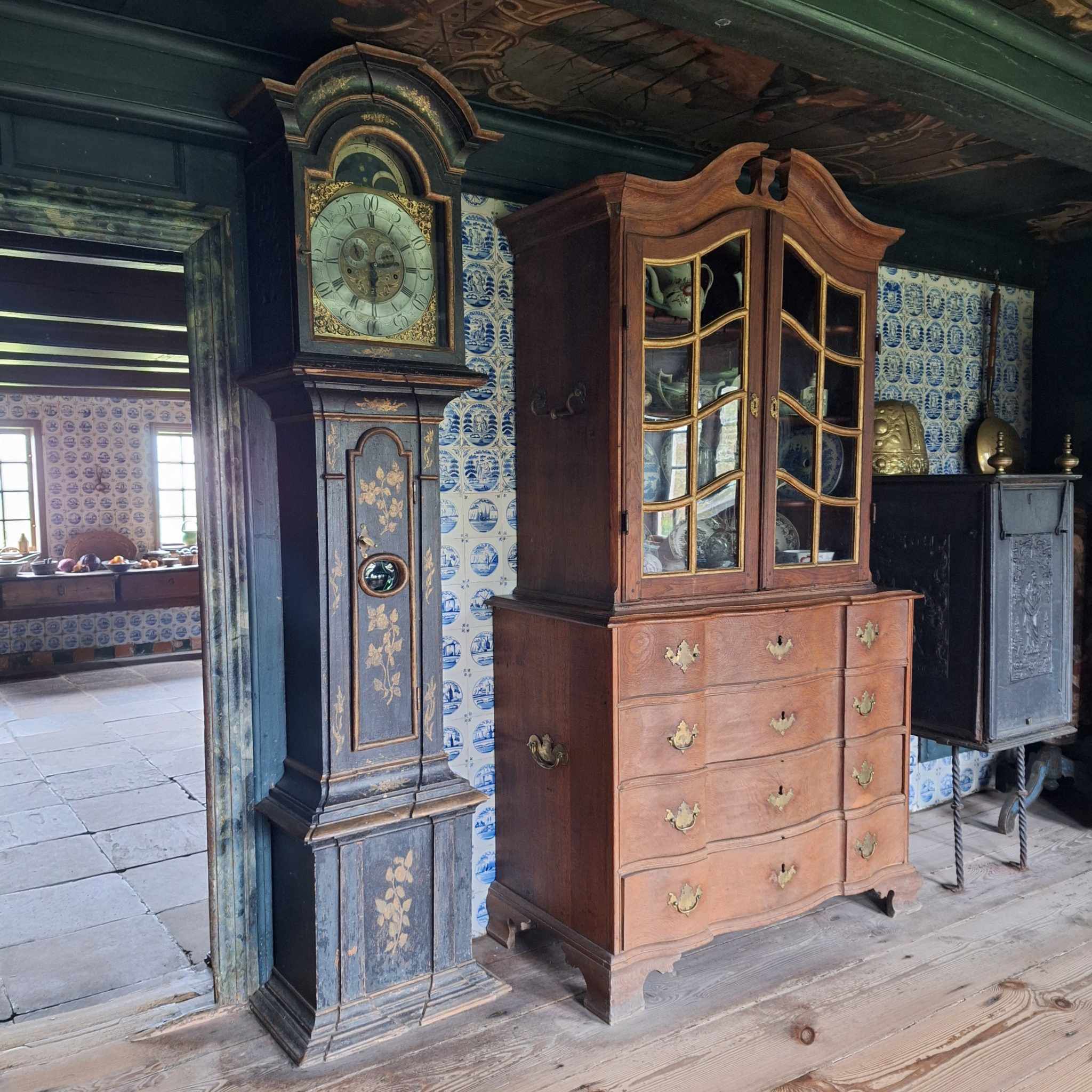 Bemalet standur og barok chatol med vitrineskab i Kommandørgårdens stue med hollandske fliser på væggene