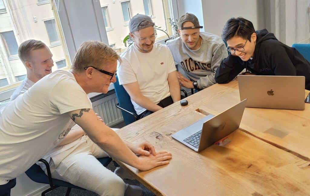 Kuvassa Petri Pystynen, Alex Lindroos, Iiro Pelttari, Mikael Gousetis ja Hung Nguyen tutkivat pöydän ääressä tietokonetta.