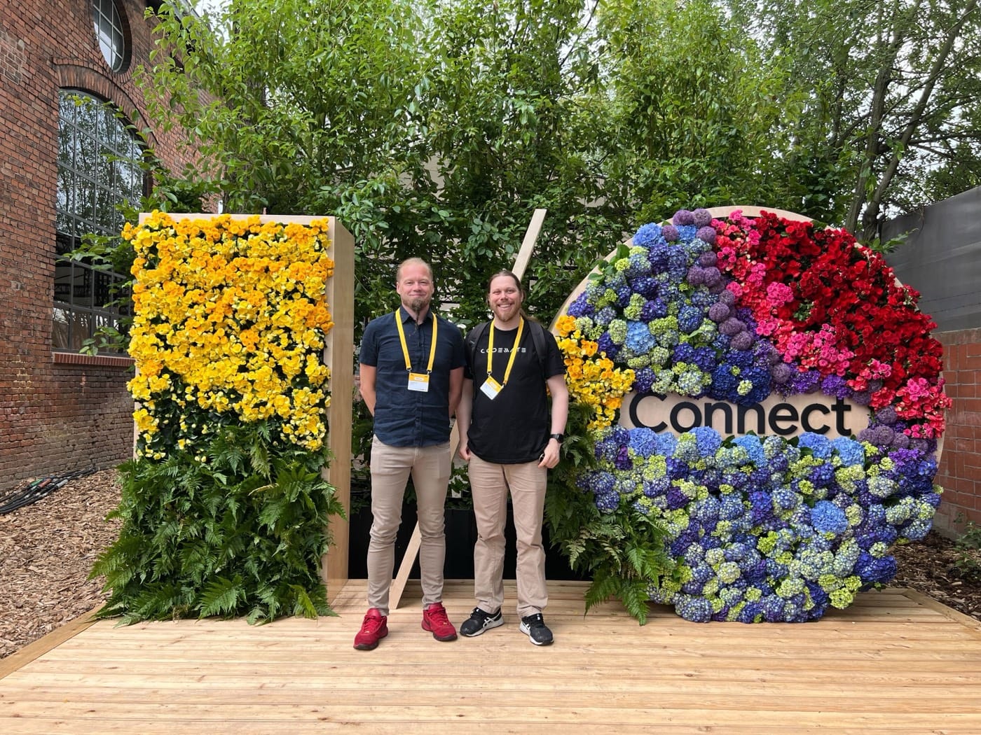 Two Codemate team members in front of the Google I/O Connect flower installation