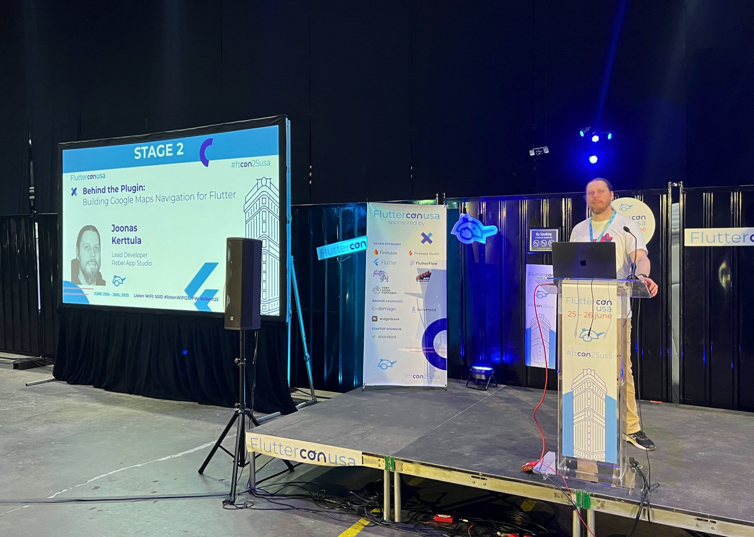 Joonas Kerttula from Rebel App Studio on stage at Fluttercon USA 2025, preparing to present 'Behind the Plugin: Building Google Maps Navigation for Flutter'.