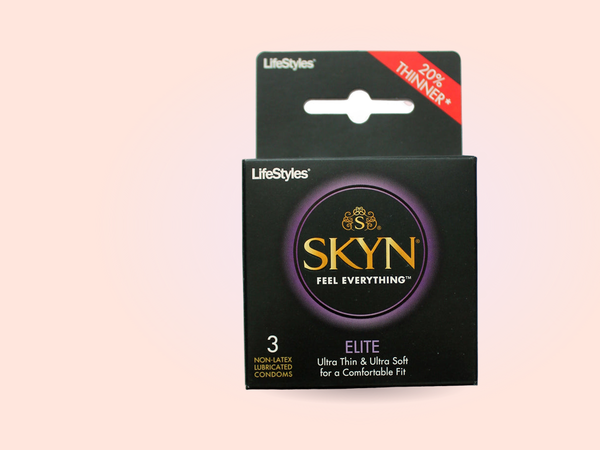 The SKYN Elite ultra-thin polyisoprene condoms box stands boldly on a warm coral backdrop, the material this guide recommends reaching for first.