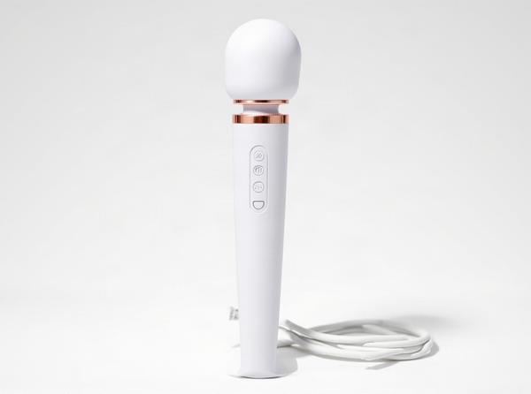 The Le Wand Plug-In wand massager stands tall in bright daylight, its cord coiled neatly beside it, a quiet moment before choosing between corded power and cordless freedom.