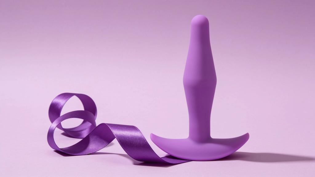 A lilac silicone plug standing upright on a pale lavender backdrop beside a curl of satin ribbon
