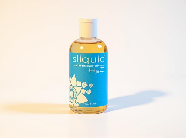 Sliquid Naturals H2O water-based lubricant bottle standing upright in warm golden daylight, the post's recommended pick for pairing lube with sex toys