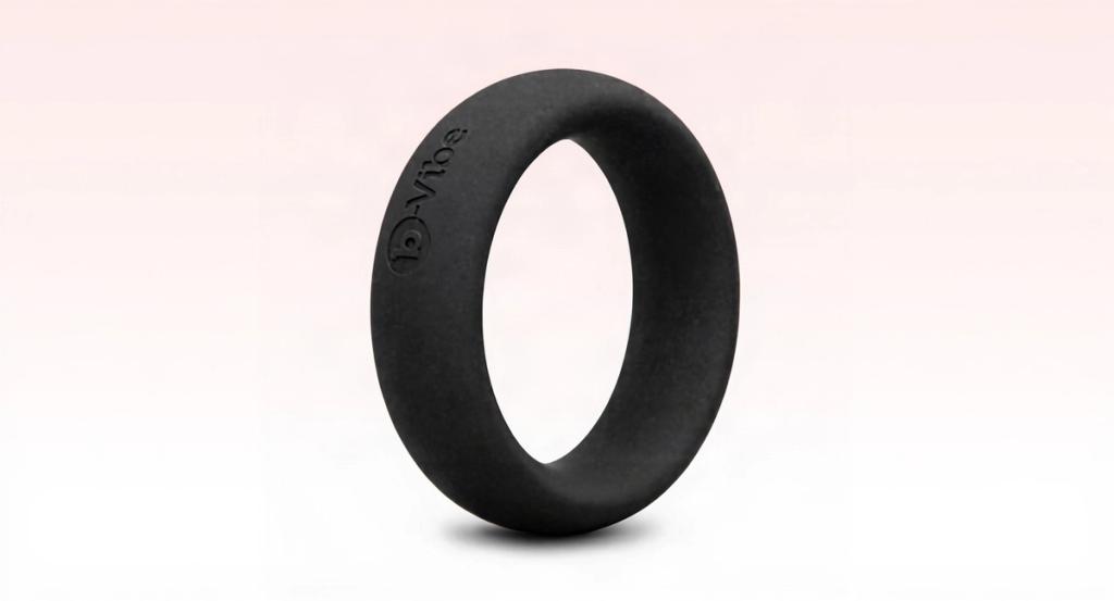 A matte-black silicone ring standing upright on a clean warm-white surface in bright daylight.