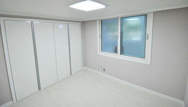 A bright, white room with wooden casing around the window and closet doors