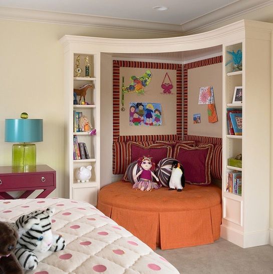 A children's reading space inset into the corner with a round couch, stuffed animals, and shelving on either side