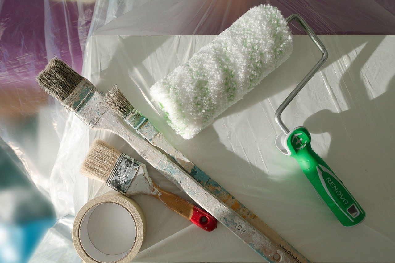 A closeup of three paintbrushes next to a roller