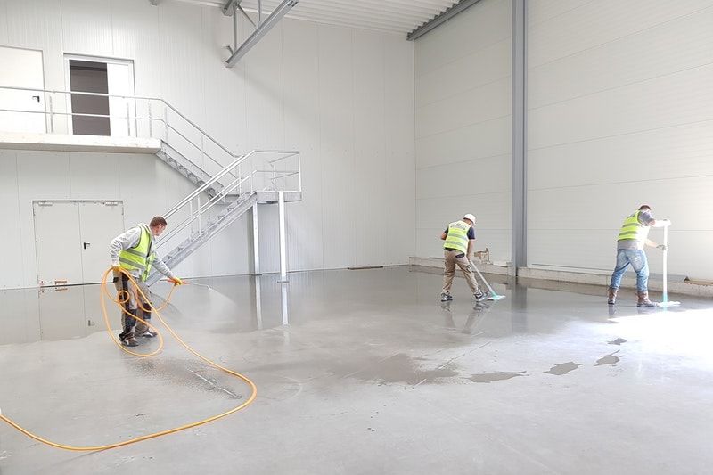 Concrete flooring being sprayed clean by professionals