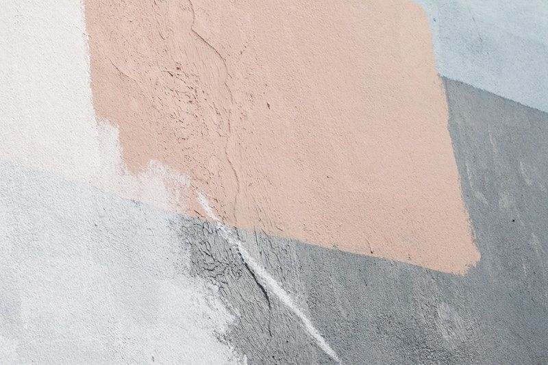 A closeup of a concrete wall with multiple paint swatches covering it