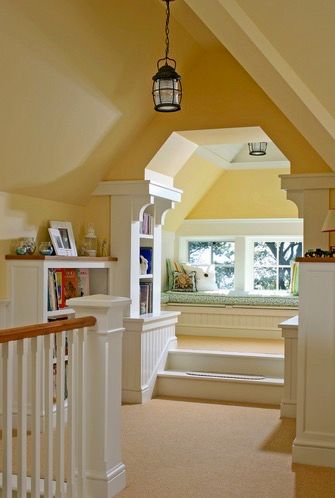 Children's reading nook with bench and pillows by window in attic with vaulted ceiling