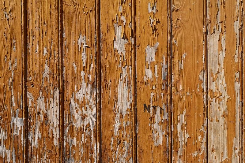 A closeup of aging wood paneling covered in chipped paint