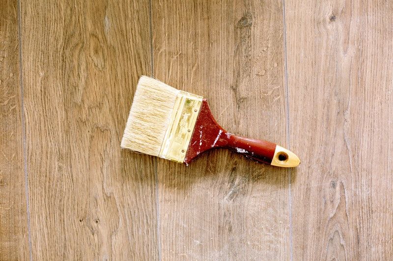 A closeup of a paintbrush on a wooden floor