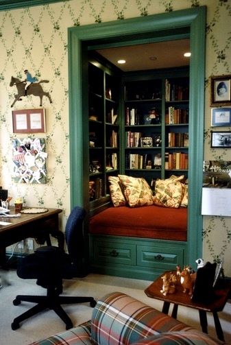 Green trimmed inset reading nook with built-in book shelves, red seating area, and yellow floral pillows