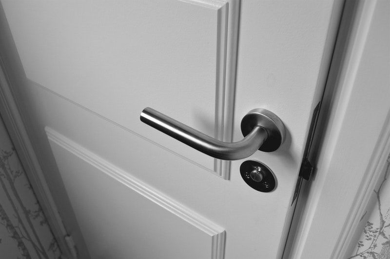 Closeup of a white door and trim with a silver handle