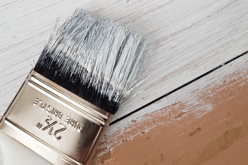 A closeup of a paintbrush placed on a partially wanted wooden surface