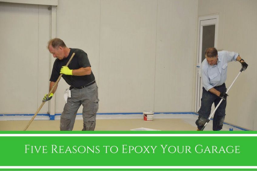 Two men applying epoxy coating on a garage floor
