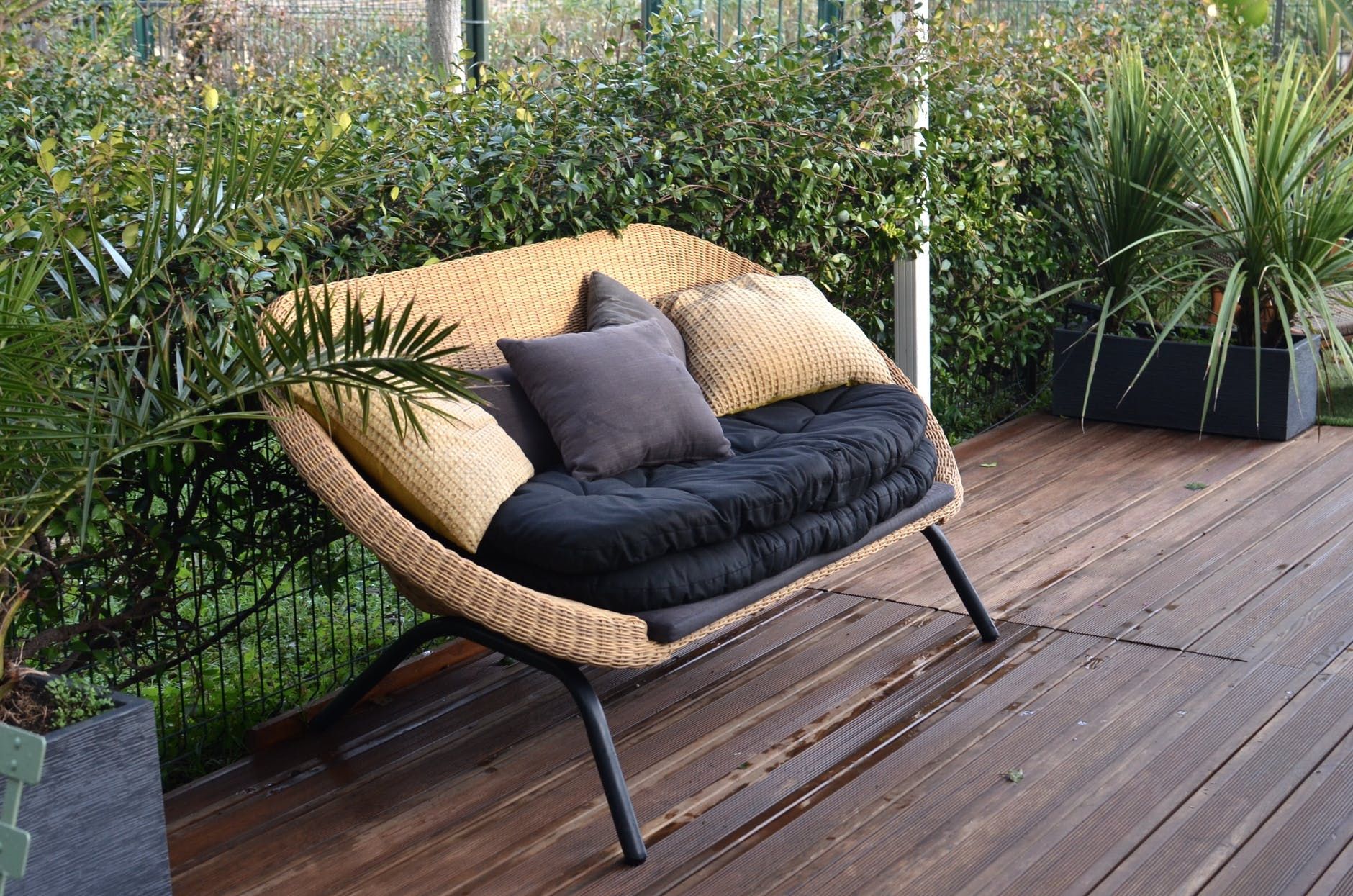 A chair next top a plant covered railing on a wooden deck