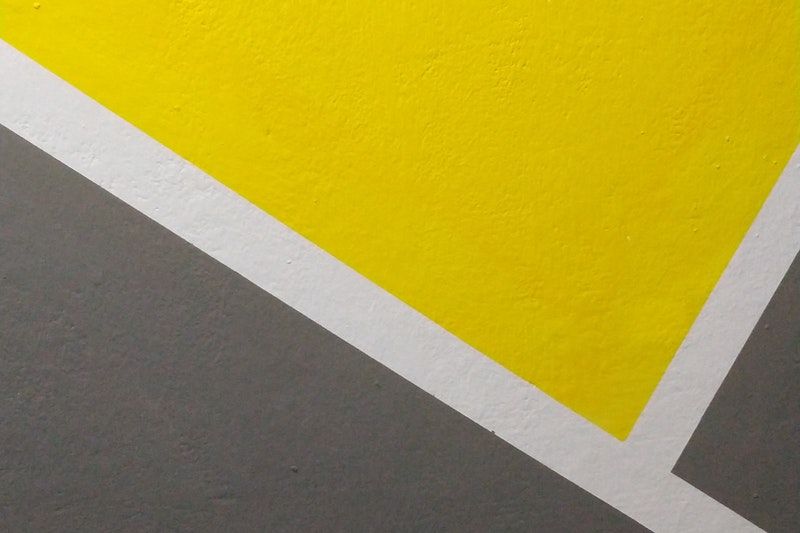 A closeup of a grey, yellow, and white design on a concrete wall
