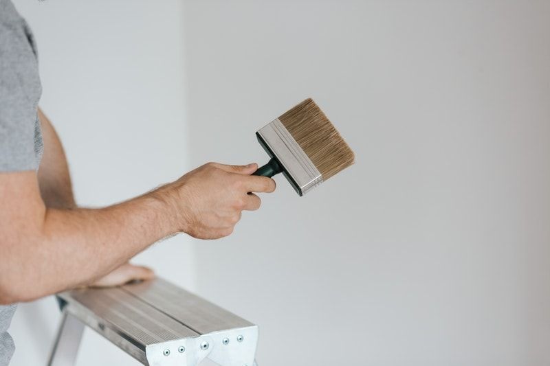 A painter holding a brush, preparing to paint a wall