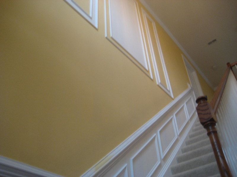 An upward shot showcasing wall frame molding along the stairs and on a yellow wall