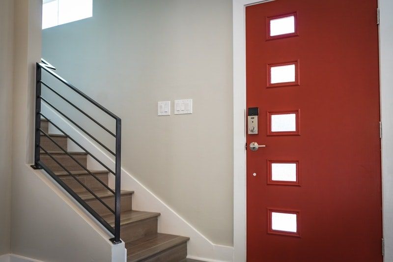The entryway of a home with a red metal door next to the stairs
