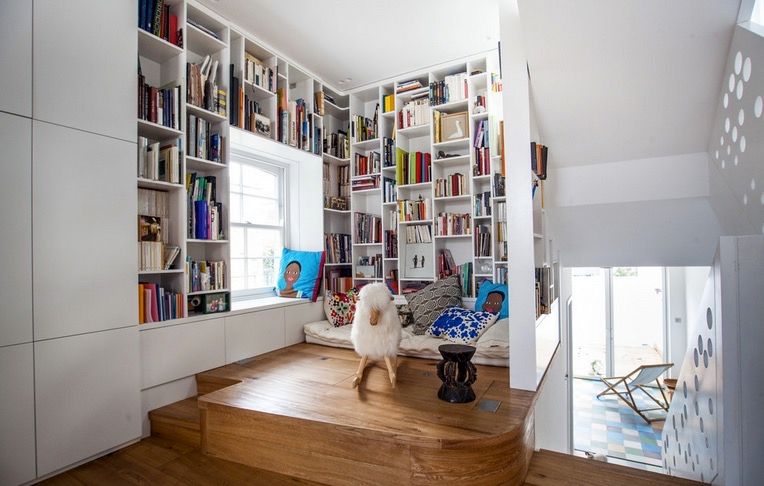 White inset book shelves with reading nook window seat and pillows at the top of a staircase