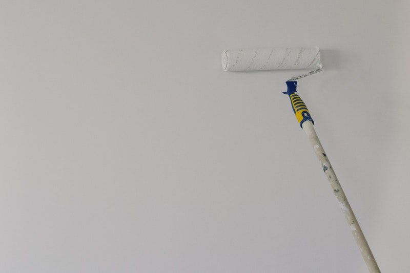 A paint roller being used to apply paint on a ceiling