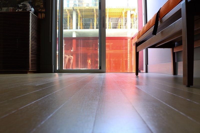 A closeup of a painted floor in the sunlight with a sliding door leading outside straight ahead