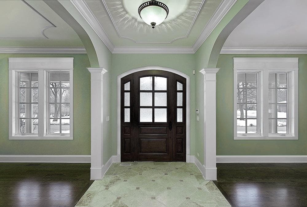 A front foyer with crown molding around the windows and doors